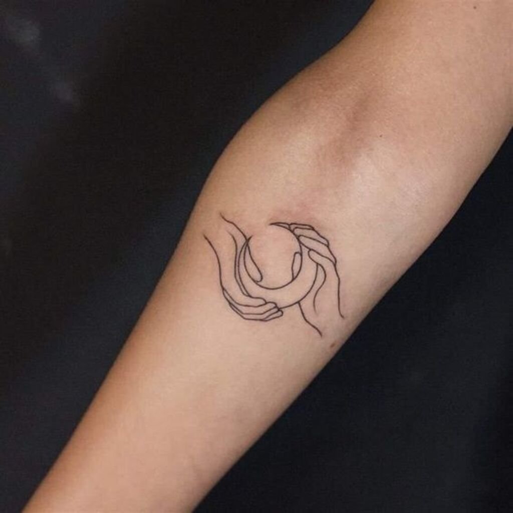 A dreamy hand tattoo of a crescent moon