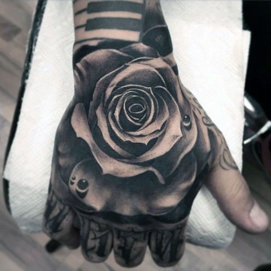 A large blackwork tattoo of flowers on the forearm and hand