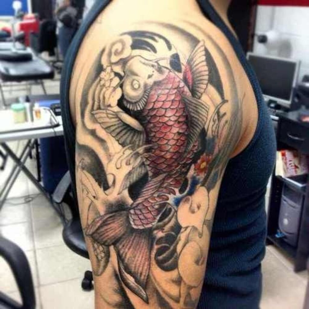 Red and black tattoos of two koi fish on a man's hand